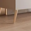A close-up view of the bottom section of a TV lowboard, showing its gold-colored metal legs resting on a wooden floor. Náhled obrázku produktu