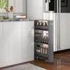 A narrow kitchen cart filled with jars of spices and other items is placed next to a white kitchen cabinet and a refrigerator. Náhled obrázku produktu