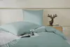 A neatly made bed with sage green bedding and a decorative deer figurine on a nightstand. Podgląd zdjęcia produktu