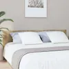 A close-up view of a bed with a wooden headboard, white bedding, and pillows. Náhľad obrázku produktu