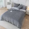 A neatly made bed with a gray striped blanket and pillows. Produktbild-Vorschau