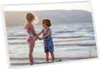 Two children are standing in shallow water at the beach, holding hands. Náhľad obrázku produktu