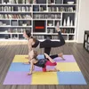 A woman and a child are doing yoga on a colorful mat in a room with bookshelves in the background. Voir les images du produit