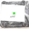 The image shows the bottom of a scale, wrapped in plastic packaging. There is a white label with a green 'A' and a barcode. Podgląd zdjęcia produktu