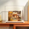 A miniature bakery and dessert shop diorama displayed inside a clear acrylic case, placed on a wooden surface. Podgląd zdjęcia produktu
