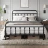 A black metal bed frame with bedding and pillows, set in a bedroom with bedside tables and wall lamps. Produktbild-Vorschau