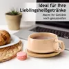 A coffee cup with a croissant and a macaron on a desk with a laptop in the background. Produktbild-Vorschau