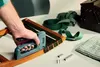 A person is using a stapler to attach green fabric to a wooden frame. Podgląd zdjęcia produktu