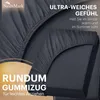Close-up of a dark gray fitted sheet, highlighting its texture and elastic edge. Text overlays describe its features. Produktbild-Vorschau