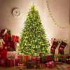 A decorated Christmas tree with presents underneath, stockings hanging, and a clock on the wall. Podgląd zdjęcia produktu