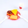 A toy meal set with a donut, cheese slice, cookie, and a drink, arranged on a red plate with a fork and knife. Produktbild-Vorschau