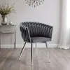 A gray velvet chair with a braided design and chrome legs, placed in a room with a glass side table and a chandelier. Anteprima dell’immagine prodotto