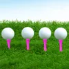 Four golf balls on pink tees on a grassy field with a blue sky in the background. Produktbild-Vorschau