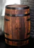 A wooden barrel-shaped cabinet with metal bands and hinges, set against a brick wall. Podgląd zdjęcia produktu