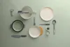 A collection of kitchenware laid out on a light green surface. Produktbild-Vorschau
