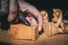 A close-up shot of a person's hands carving a wooden object with a knife. Anteprima dell’immagine prodotto