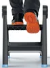 A person's feet wearing work shoes are stepping onto a black step stool. Podgląd zdjęcia produktu