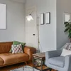 A living room scene with a leather sofa, armchair, floor lamp, and side table. Produktbild-Vorschau