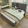 A bedroom scene featuring a bed with bedding, a headboard with integrated charging ports, and a bedside table. Produktbild-Vorschau