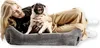 A woman is lying down with a pug on a dog bed. Produktbild-Vorschau