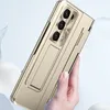 A hand holding a gold-colored phone case with a built-in stand and camera cutout. Náhled obrázku produktu