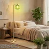 A bedroom scene with a bed, a nightstand, plants, and a floor lamp. Anteprima dell’immagine prodotto