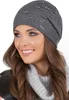 A woman wearing a dark gray beanie with pearl and rhinestone embellishments and a gray cowl neck sweater. Náhled obrázku produktu