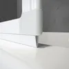 Close-up view of the bottom corner of a white shower enclosure, showing its connection to the floor and wall. Produktbild-Vorschau