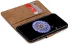 A brown leather wallet-style phone case with two cards inserted, showing a smartphone screen with a dandelion image. Produktbild-Vorschau