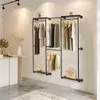 A clothing rack with clothes hanging on it, placed against a wall in a room with a rug and a table. Produktbild-Vorschau