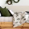 A cozy bed with a winter-themed duvet cover and pillows, decorated with wreaths. Produktbild-Vorschau