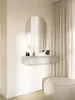 A modern vanity or console table with a drawer, mirror, and decorative items against a wall with curtains and a pouf. Náhľad obrázku produktu