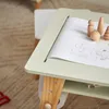 A close-up view of a child's activity table with a drawing and wooden toys. Produktbild-Vorschau