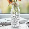 A glass bottle filled with clear water beads and orange flowers, placed on a windowsill. Produktbild-Vorschau