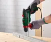 A person wearing gloves is using a Parkside drill to drill into a metal bar on a wooden workbench. Produktbild-Vorschau