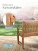 A wooden garden bench is shown on a wooden deck with a blurred background of trees and flowers. Produktbild-Vorschau