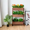 A wooden planter with three tiers, filled with plants and flowers, is displayed indoors. Náhled obrázku produktu
