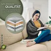 A woman is sitting on a couch, wrapped in a heated blanket and reading a book. An infographic detailing the blanket's layers is shown on the left. Produktbild-Vorschau
