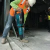 A construction worker using a demolition hammer on a concrete floor. Anteprima dell’immagine prodotto