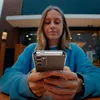 A woman is holding a smartphone with a transparent case. Produktbild-Vorschau