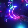 A hand holding a crescent moon-shaped LED light decoration with other star-shaped lights in the background. Produktbild-Vorschau