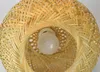 A close-up view of a woven bamboo lampshade with a light bulb inside. Produktbild-Vorschau