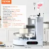 A white cake decorating machine with a cake on its turntable, set in a kitchen environment. Náhľad obrázku produktu