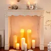 A white fireplace console decorated with various candles of different sizes and heights, creating a warm and inviting ambiance. Produktbild-Vorschau