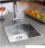 A stainless steel kitchen sink with a faucet, a cake decorated with strawberries, and a bowl of fruit on a countertop. Produktbild-Vorschau