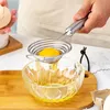 A person is using a stainless steel egg separator to separate the yolk from the egg white into a glass bowl. Produktbild-Vorschau