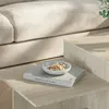 A close-up shot of a coffee table with a book and a bowl of pistachios on it, with a couch in the background. Náhled obrázku produktu
