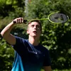 A young man playing badminton outdoors. Produktbild-Vorschau