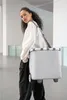 A woman is carrying a shopping trolley bag over her shoulder in an indoor setting. Produktbild-Vorschau