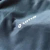 A close-up of a grey fabric with a white Lotto logo and text. Produktbild-Vorschau